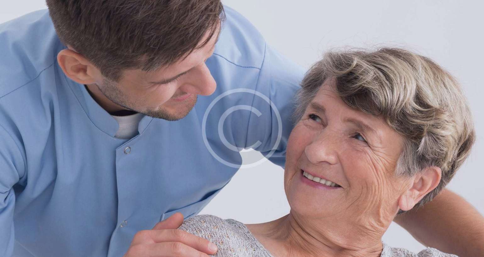 Caregiver comforting and smiling with elderly woman.