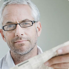 Man with glasses holding a newspaper.